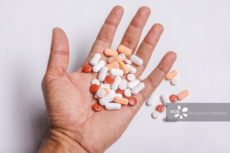手中的药丸和药物，白色背景。药物过量概念图片素材