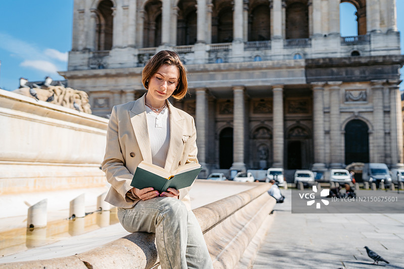 在法国巴黎圣叙尔皮斯教堂前阅读书籍的大学生图片素材