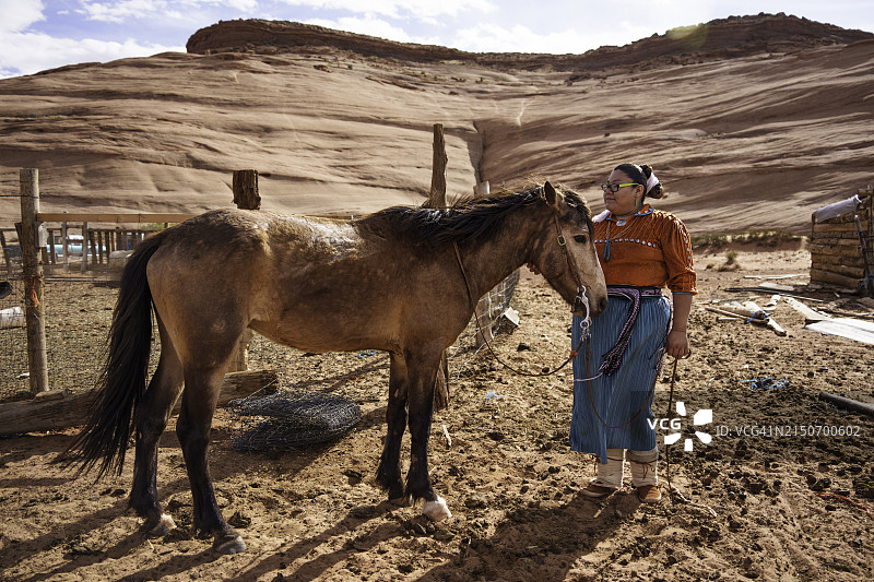 在纪念碑谷部落公园，年轻的纳瓦霍族夫妇在家庭牧场上骑马图片素材