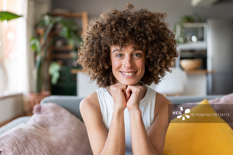 坐在沙发上微笑的卷发女人图片素材