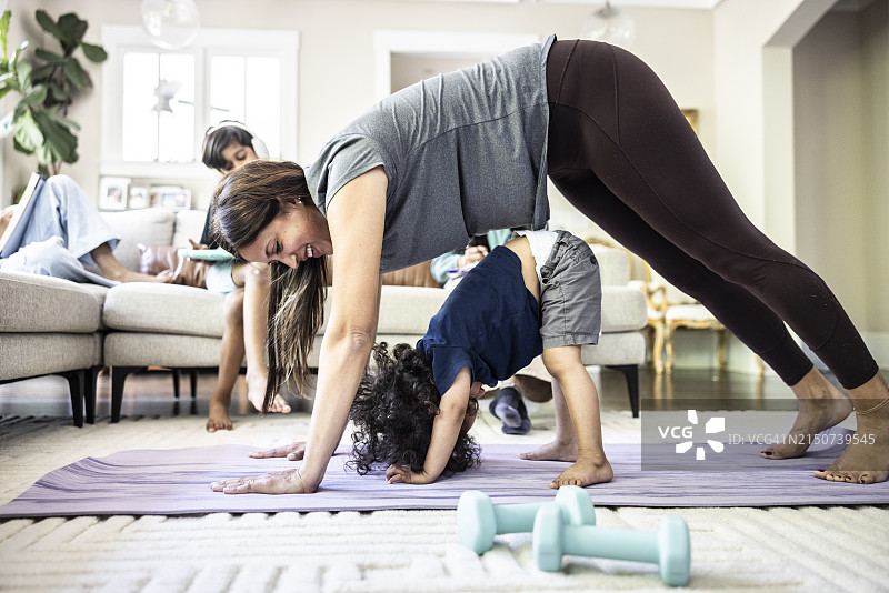 母亲在家锻炼，儿子在一旁图片素材
