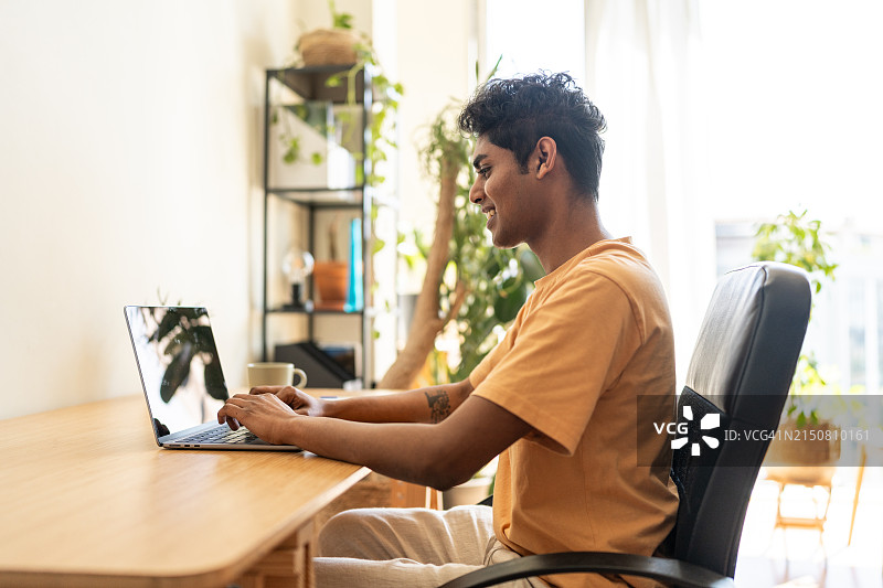 男子坐在办公桌前，面前放着一台打开的笔记本电脑图片素材
