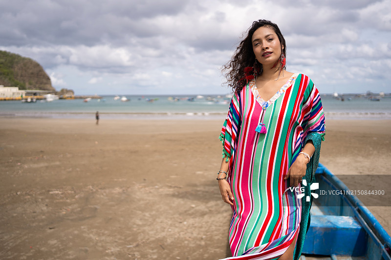 拉丁裔女性身穿鲜艳飘逸的连衣裙，以海滩为背景图片素材