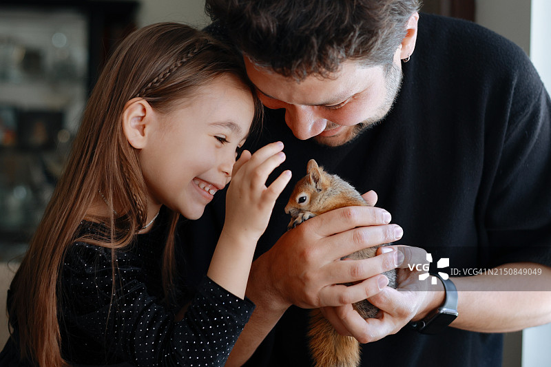 年轻女孩和父亲与小松鼠玩耍图片素材