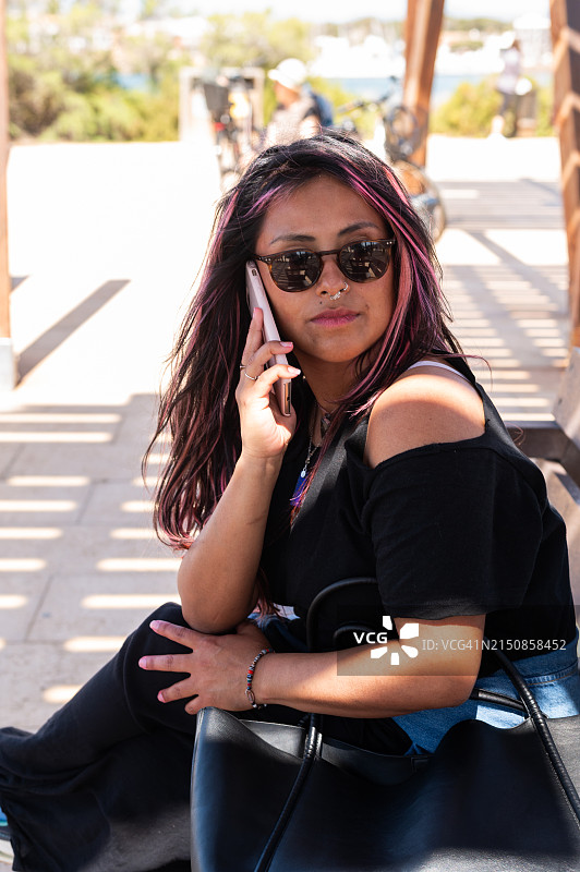 女人坐在沙滩椅上用手机交谈图片素材