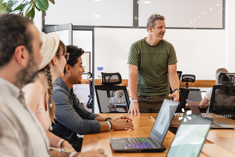 年轻创业者团队聚集在明亮的现代化办公室里，使用笔记本电脑图片素材