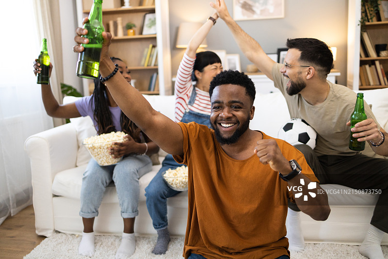 一群快乐的朋友在家看电视体育比赛时欢呼图片素材