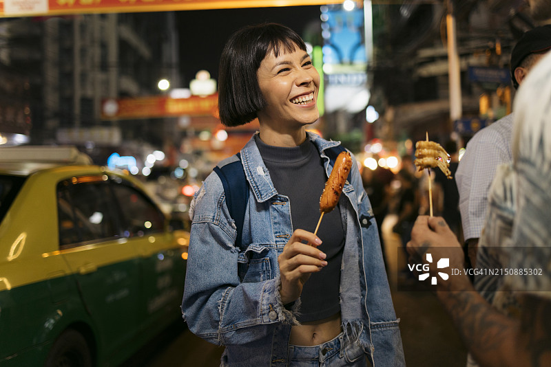 在城市街道上吃街头小吃的微笑旅行情侣图片素材