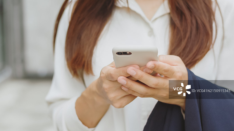 在城市街道使用智能手机的亚洲女商人特写镜头图片素材