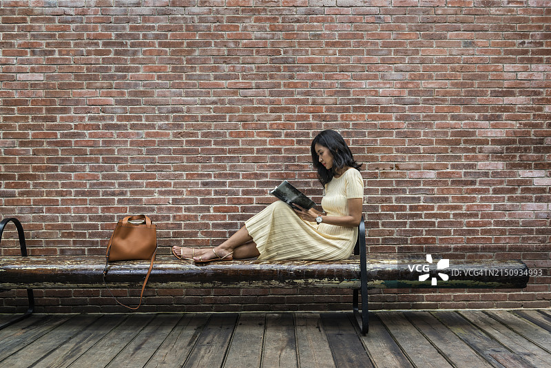 在城市街道长椅上看书的年轻女人图片素材