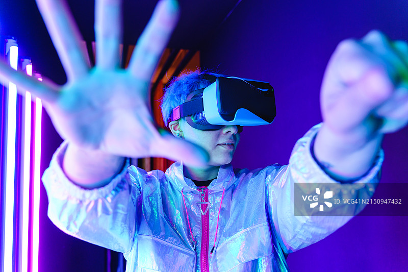 未来主义人像：佩戴VR眼镜的年轻女性和彩色霓虹灯图片素材