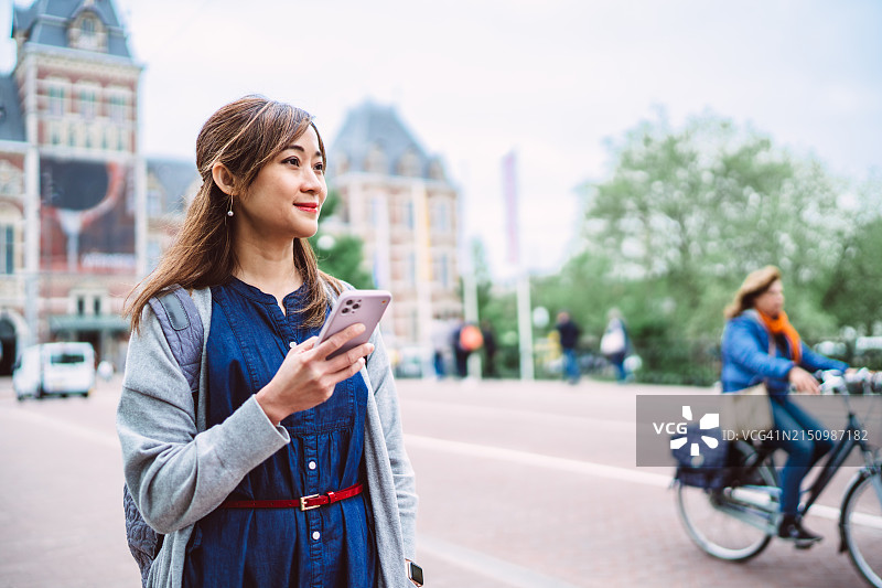 旅行中的互联：年轻亚裔女性使用手机App导航和查找位置图片素材
