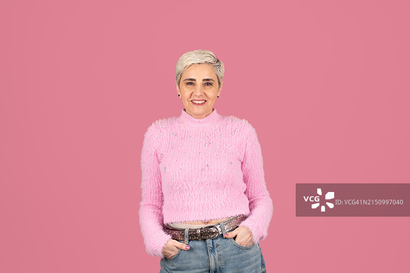 穿着休闲的中年妇女对着镜头微笑，手放在口袋里图片素材