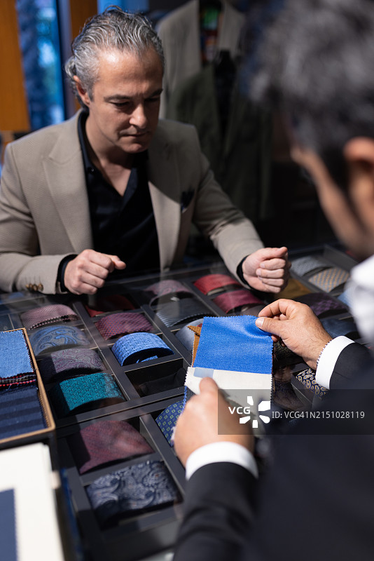 自信的商人检查裁缝展示的新西装面料图片素材