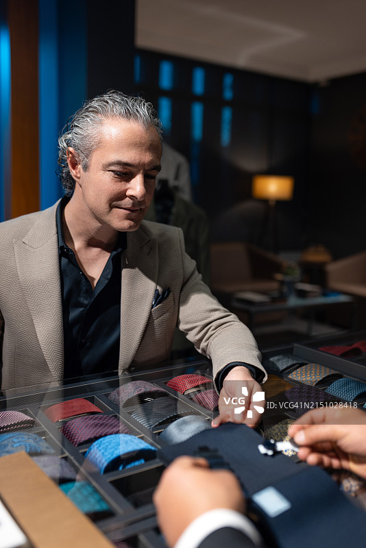 自信的商人检查裁缝展示的新西装面料图片素材
