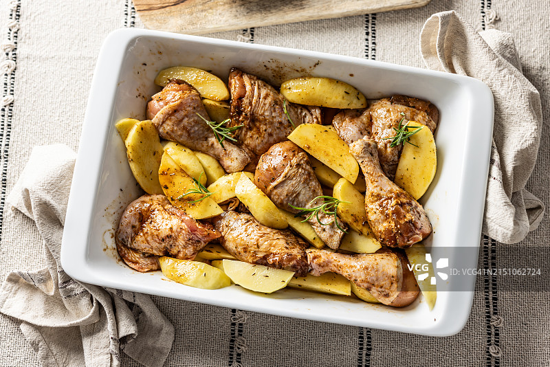 准备放入烤箱的调味生鸡腿和土豆片。烘烤准备图片素材