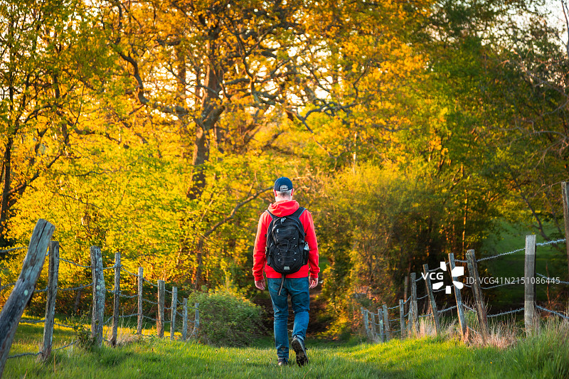 在日落时分乡村小路上徒步的背包客图片素材