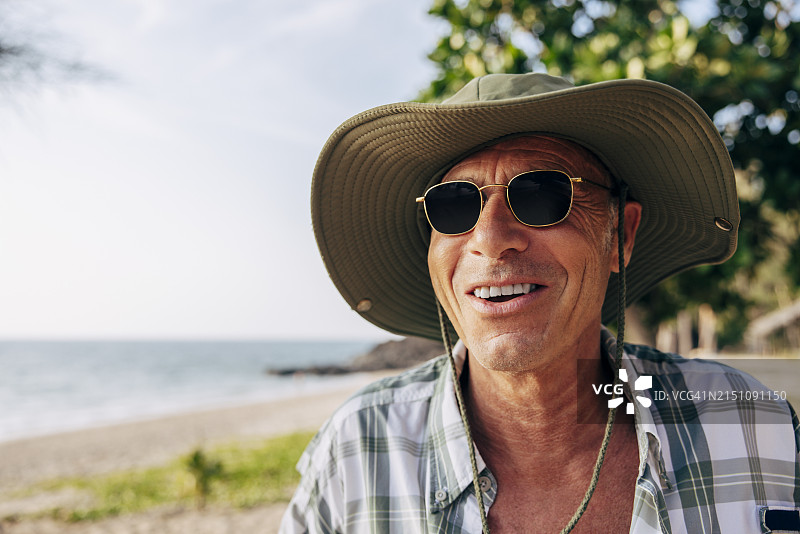 在海滩度假时戴着太阳镜和帽子的微笑老年男人图片素材