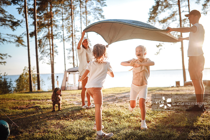 湖畔家庭乐：兄妹在吊床上玩耍，父母在松树林中陪伴，女儿患有唐氏综合征图片素材