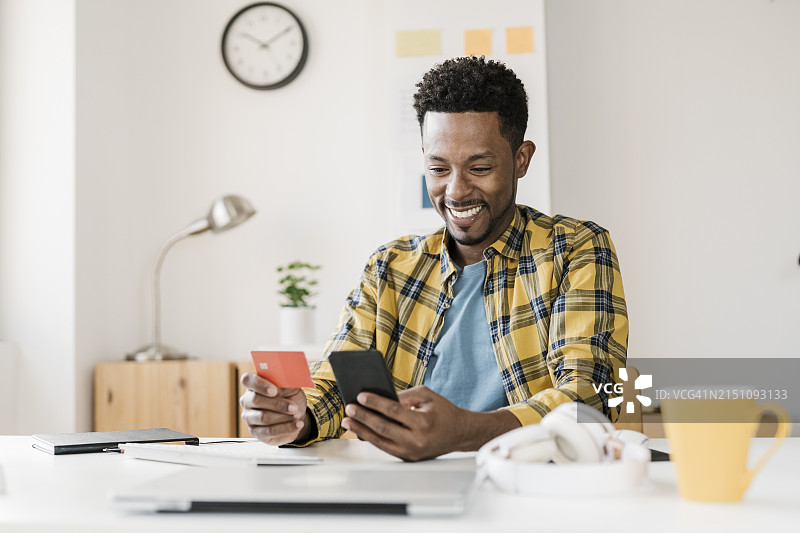 非裔男人在家居办公室用手机在线购物图片素材