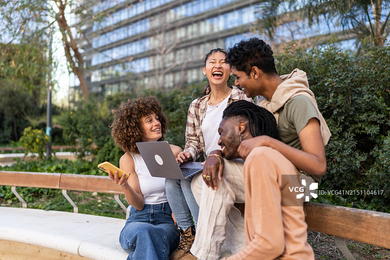 朋友们在户外共享一台笔记本电脑图片素材