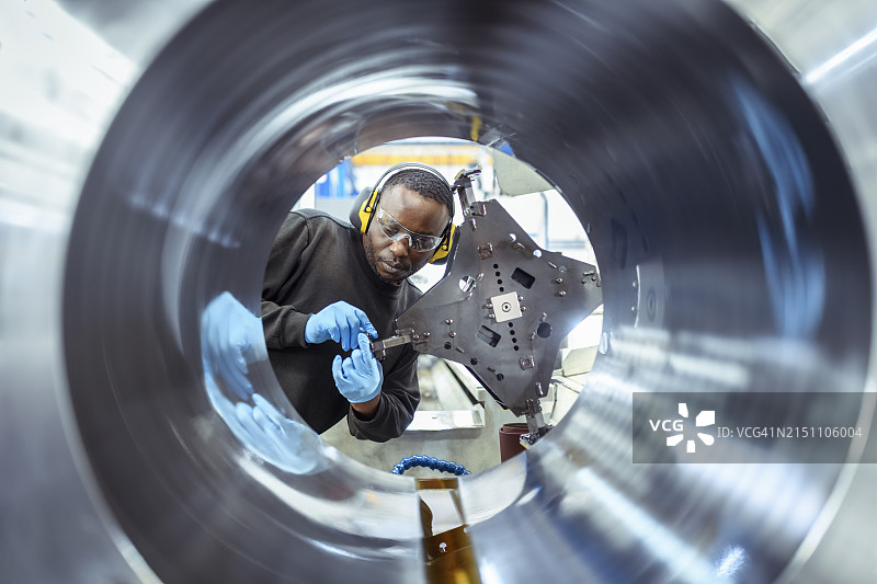 在工程工厂里，工程师手持切割工具切割大型零件图片素材