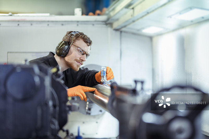 工程师在工程工厂中使用超声波探伤对车床上钢件进行裂纹测试图片素材