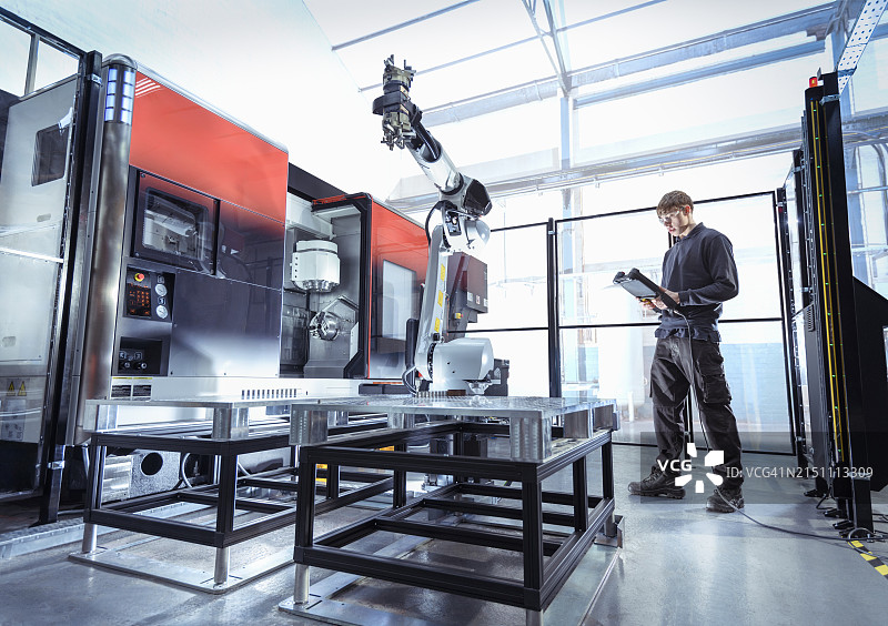 工程师在工程工厂的数控机床上对机器人进行编程图片素材