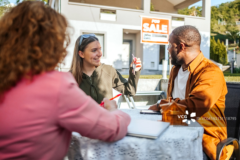 房产中介向年轻夫妇出售房屋，洽谈签约图片素材
