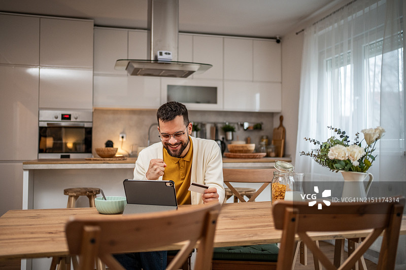快乐的男人使用平板电脑查看他的银行账户图片素材