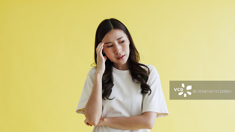 黄色背景上头痛的焦虑亚洲女人图片素材
