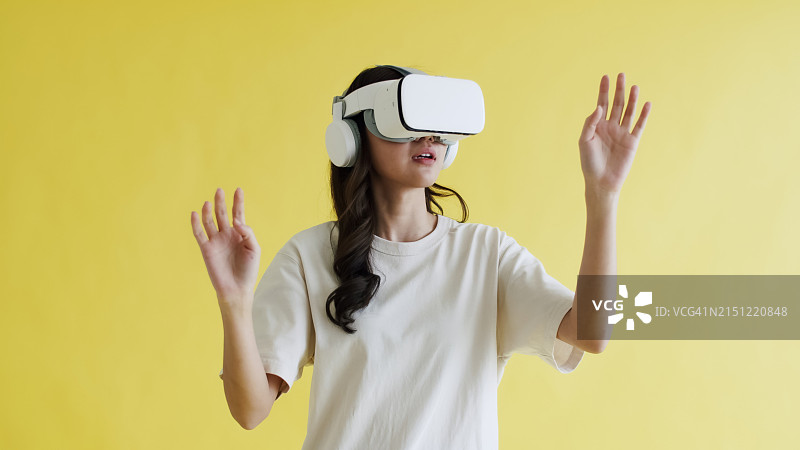 亚洲女人使用VR设备，黄色背景图片素材