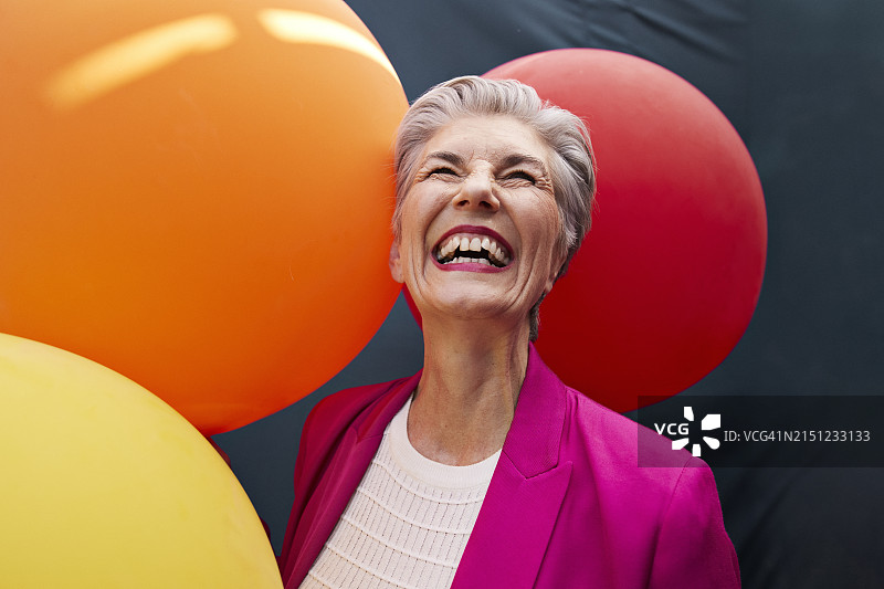 笑容满面的老年妇女拿着气球抬头图片素材
