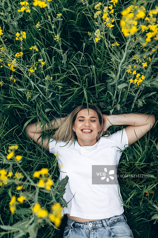 躺在盛开油菜花田里的美丽女子肖像图片素材