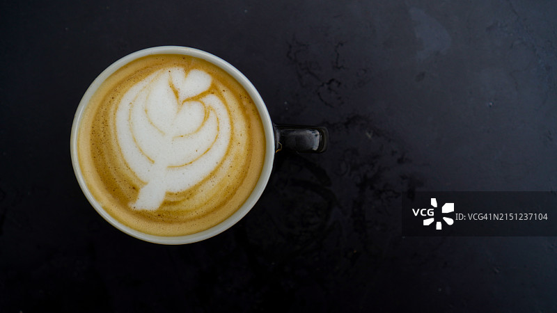 黑色桌子上的拉花拿铁图片素材