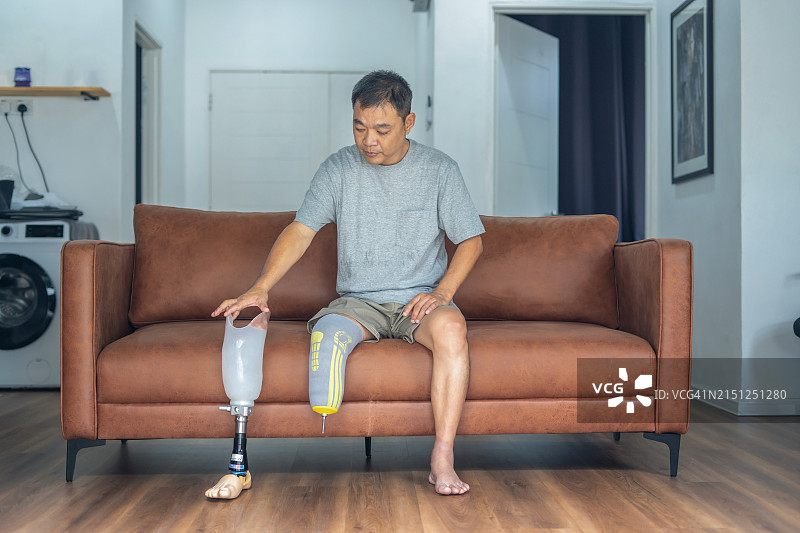 男人坐在沙发上，手持假肢图片素材