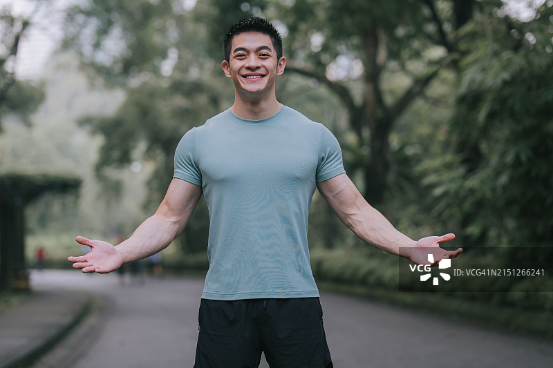 在公园里微笑看着镜头的亚洲男运动员图片素材