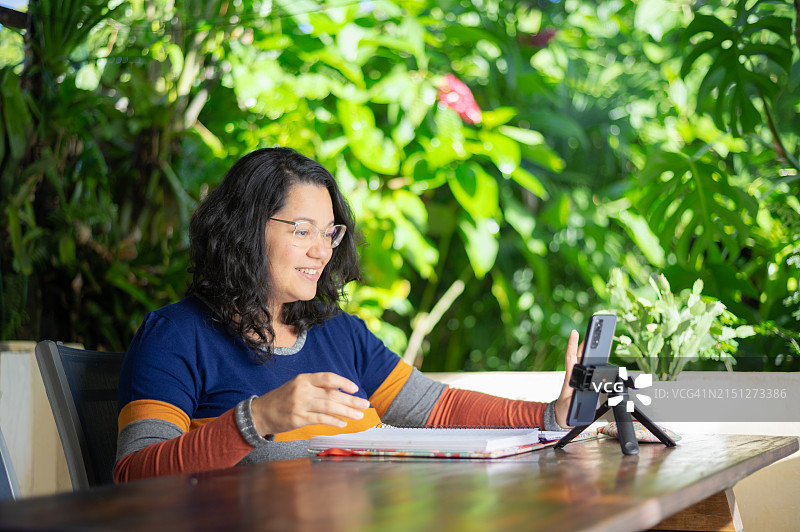 居家办公：女人在在线视频会议中做笔记图片素材