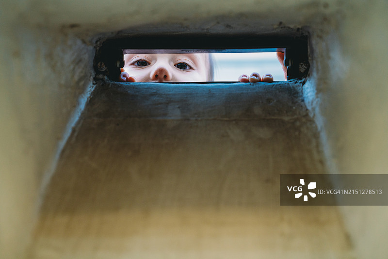 透过墙洞看镜头的男婴图片素材