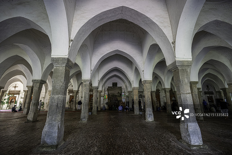 巴盖尔哈特六十拱清真寺内的祈祷者，周围环绕着石柱和白色拱门，联合国教科文组织遗产图片素材