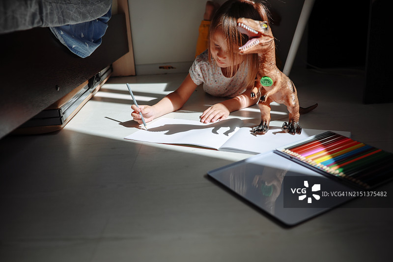 创意儿童：在地板上用彩色铅笔画恐龙，早期学习和想象力图片素材