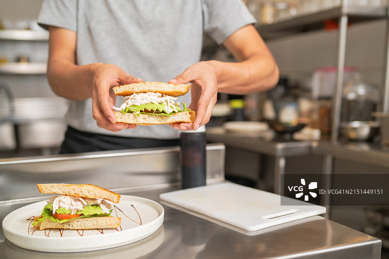 厨师在自助餐厅厨房完成鸡肉三明治的装盘图片素材