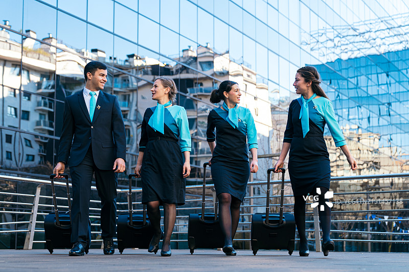 航空公司机组人员在机场航站楼外自信地行走图片素材