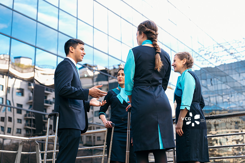 航空公司机长在玻璃航站楼与机组人员讨论计划图片素材