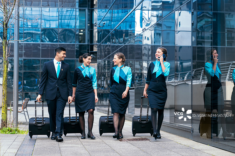 快乐的航空公司机组人员在航站楼行走时分享笑声图片素材