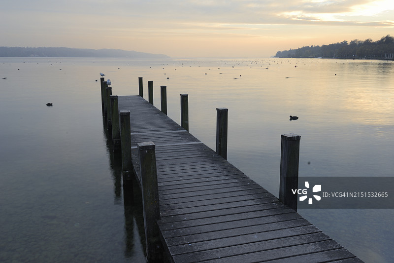 日落时分施塔恩贝格湖上的木制码头，位于德国巴伐利亚州施塔恩贝格图片素材