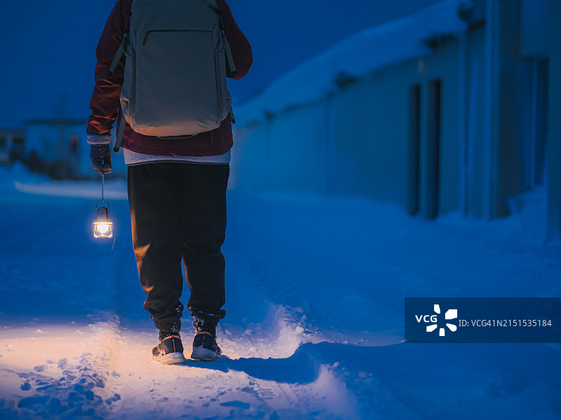 在冰岛格伦达菲厄泽小镇冬季旅行，手持电灯的年长中国女性游客图片素材