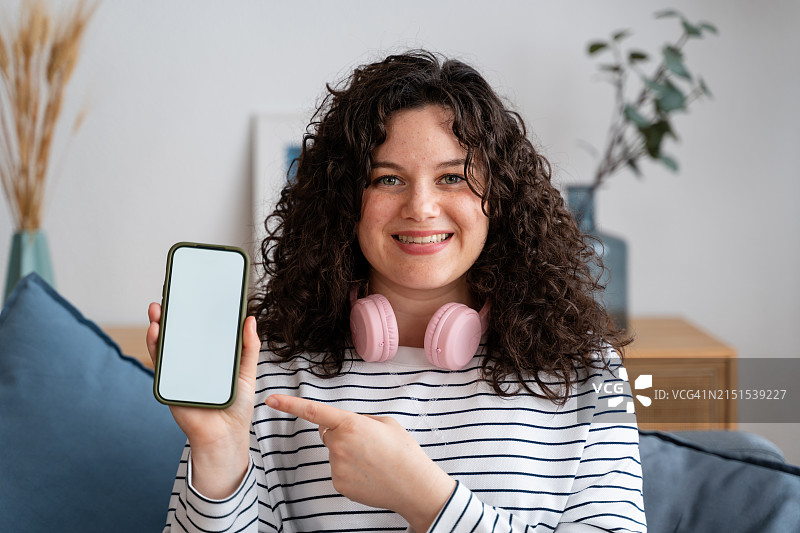 微笑的女人展示带有空白屏幕的智能手机图片素材