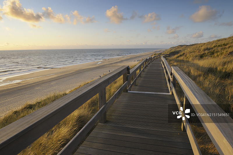 傍晚穿过沙丘的木板路；欧洲，德国，石勒苏益格荷尔斯泰因州，叙尔特岛，北弗里西亚群岛，坎彭，北海图片素材