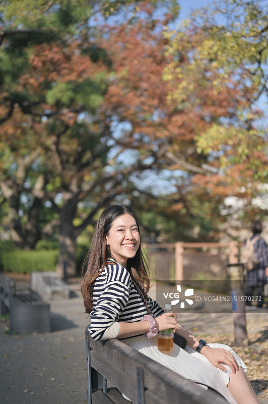 在大阪公园枫树下散步的Z世代亚洲女子图片素材